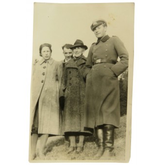 Немецкий унтер-офицер в шинели фотографируется с гражданскими лицами. Espenlaub militaria